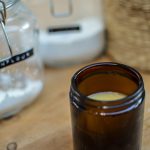 DIY deodorant in an amber glass jar on a wooden table, next to glass jars filled with cornstarch and sodium bicarbonate